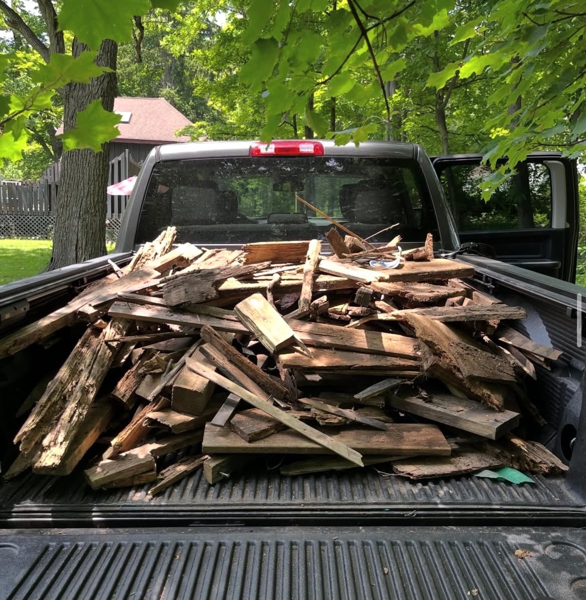 Weathered wooden boards and scrap lumber piled high in the bed of a pickup truck.