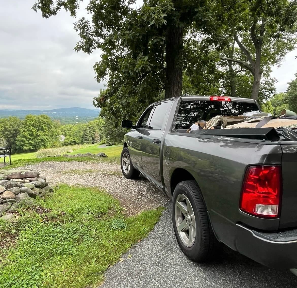 Gray pickup truck with a loaded bed parked on a driveway overlooking scenic mountains.
